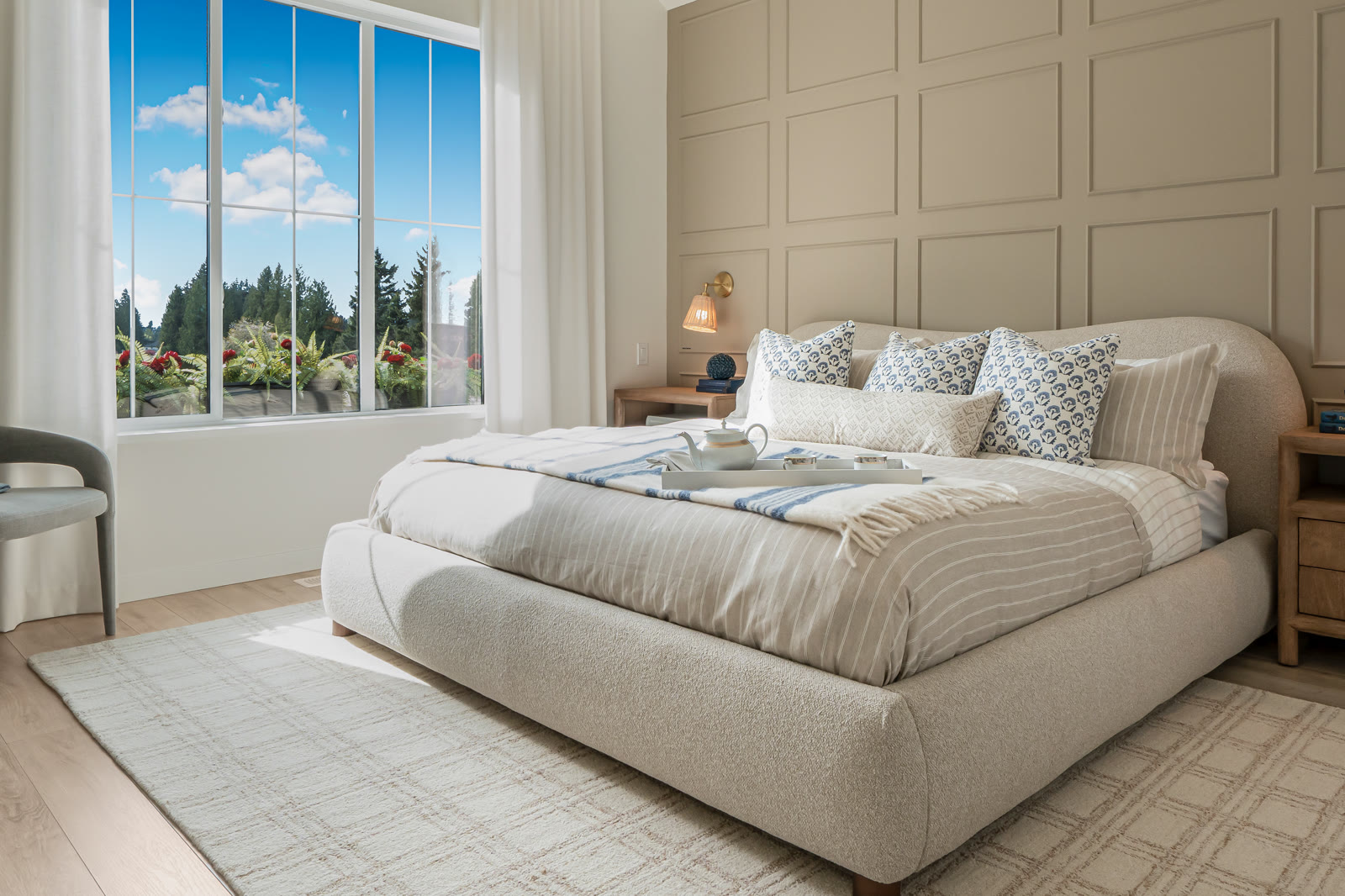 Staged primary bedroom with panelled accent wall and garden view