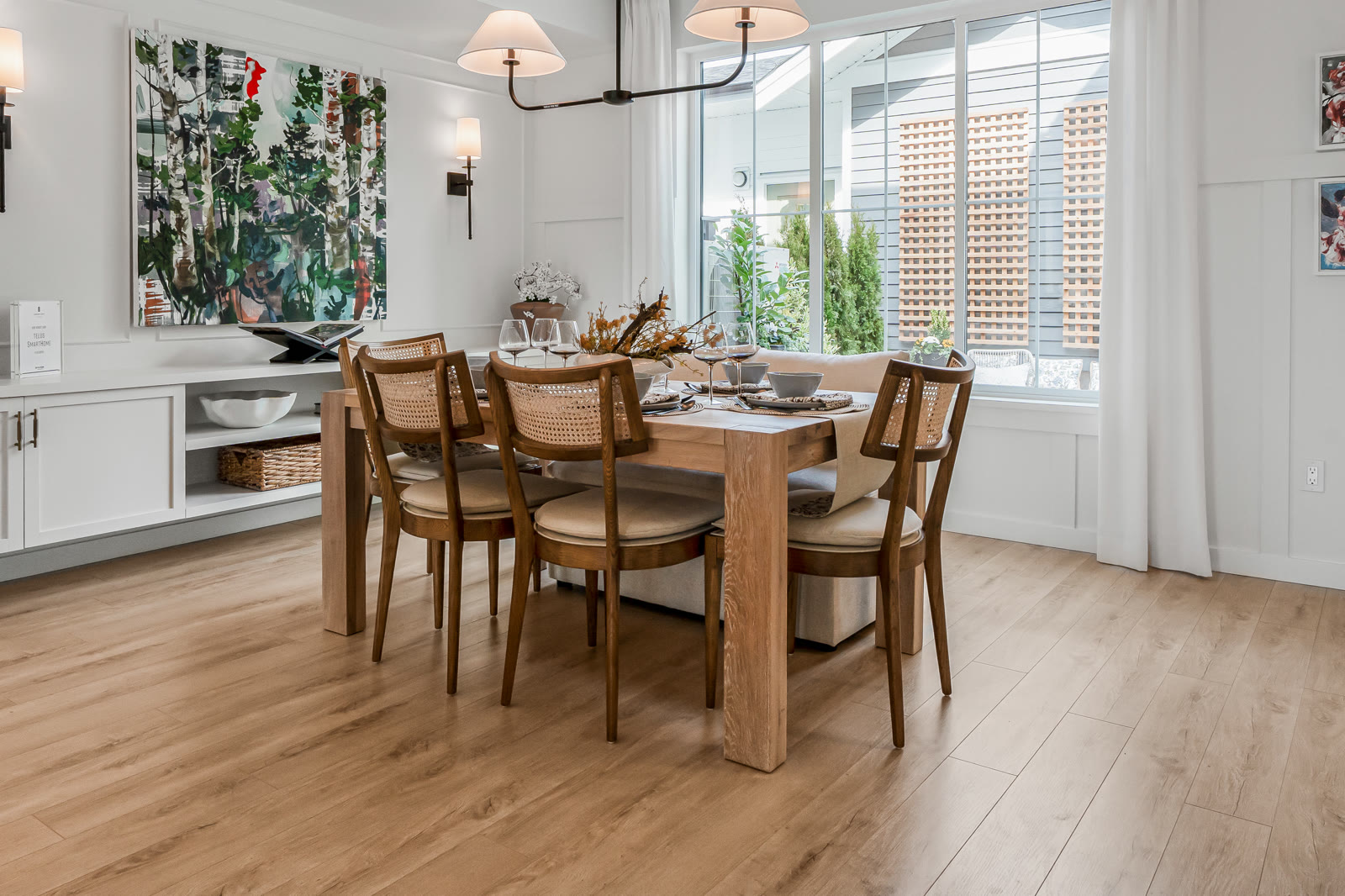 Bright staged dining room with cane chairs and feature artwork